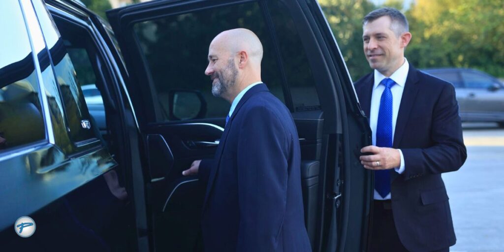 A professional chauffeur from Peak Limo opens the door for a client in a luxury SUV, illustrating the difference between a chauffeur vs driver service.