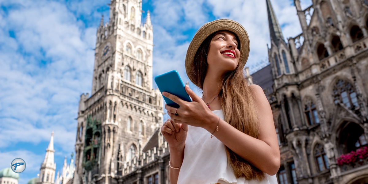 Smiling woman holding a smartphone while exploring a historic European city square, enjoying seamless travel abroad with smart transportation planning.