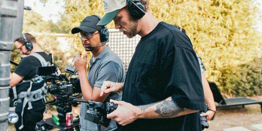 Film crew in headsets reviews a camera monitor on an outdoor movie set, where film production transportation in Charlotte keeps cast and crew on schedule.